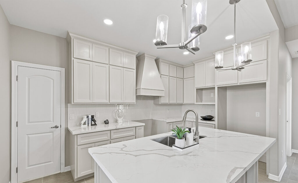 A bright kitchen with sleek white cabinetry and luxurious marble countertops, showcasing a contemporary aesthetic.